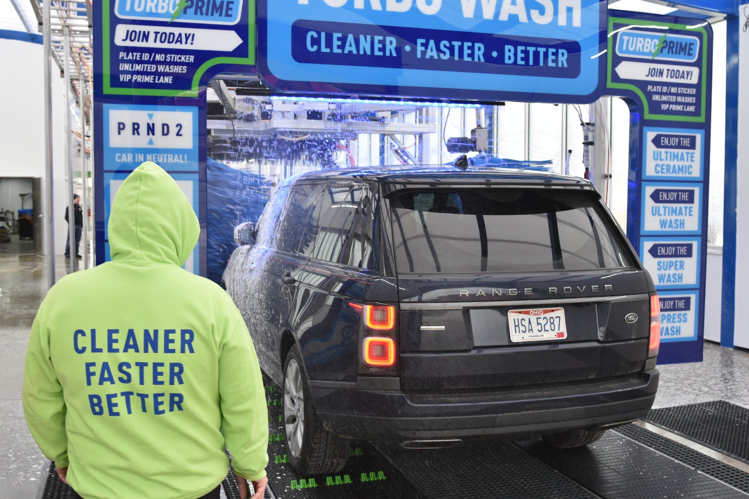 A Turbo Wash attendant guiding a car onto the conveyor belt